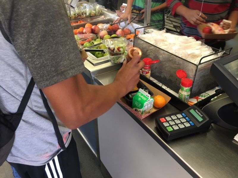 Photo of student's hand shaking spices on food