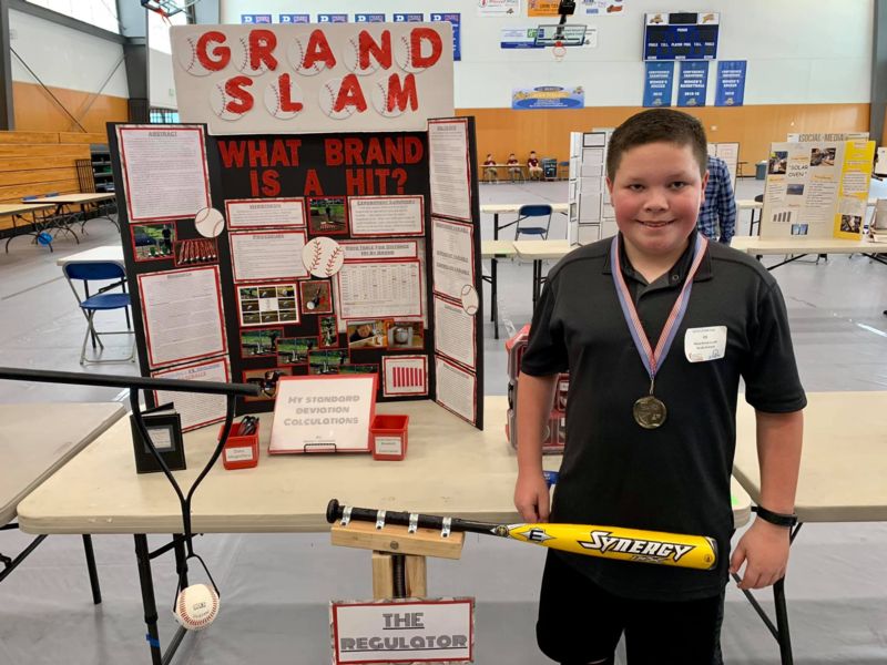 Brady Hickman posing next to his science fair project